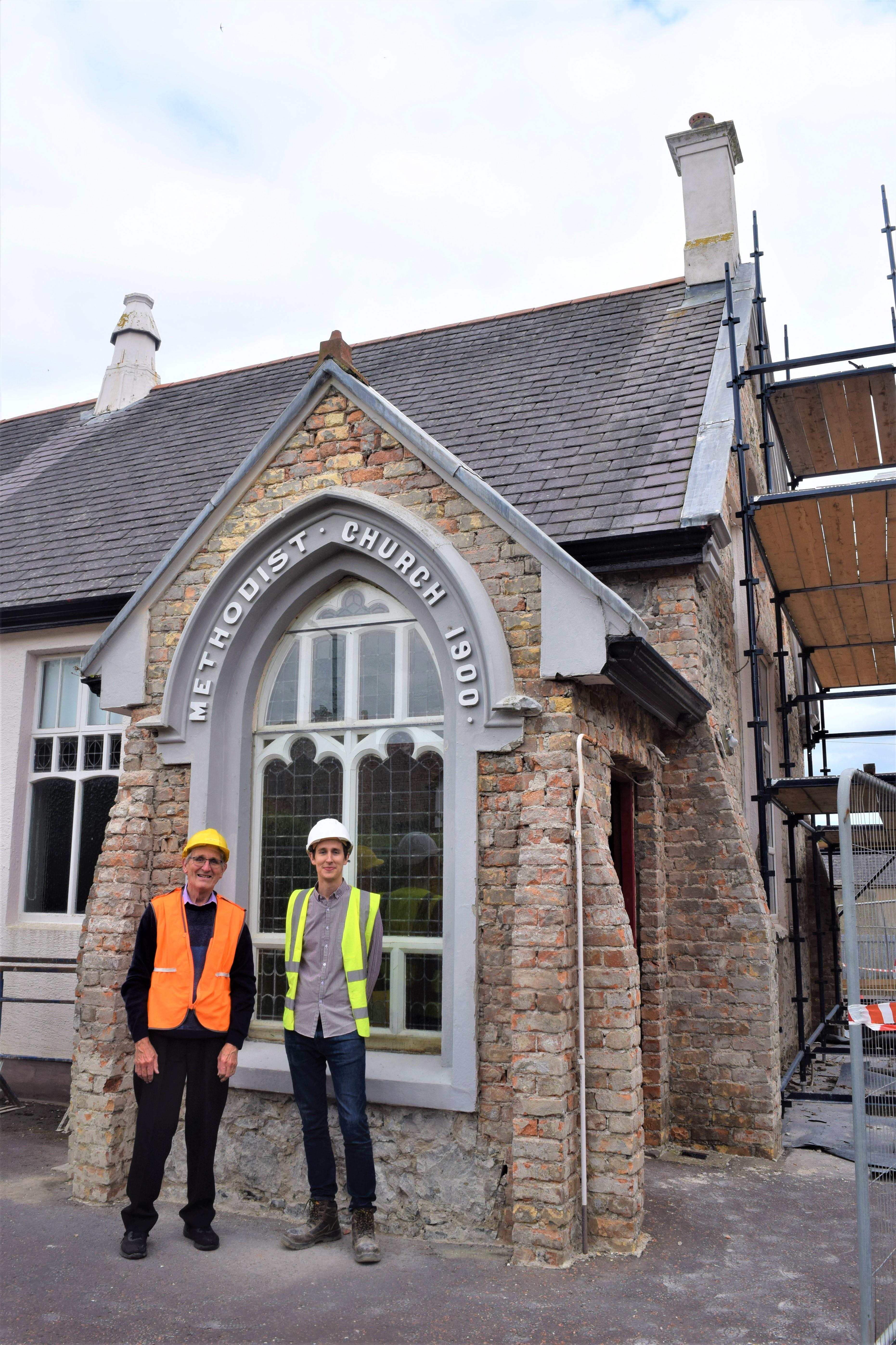 Two people with his-vis jackets standing in front of a church