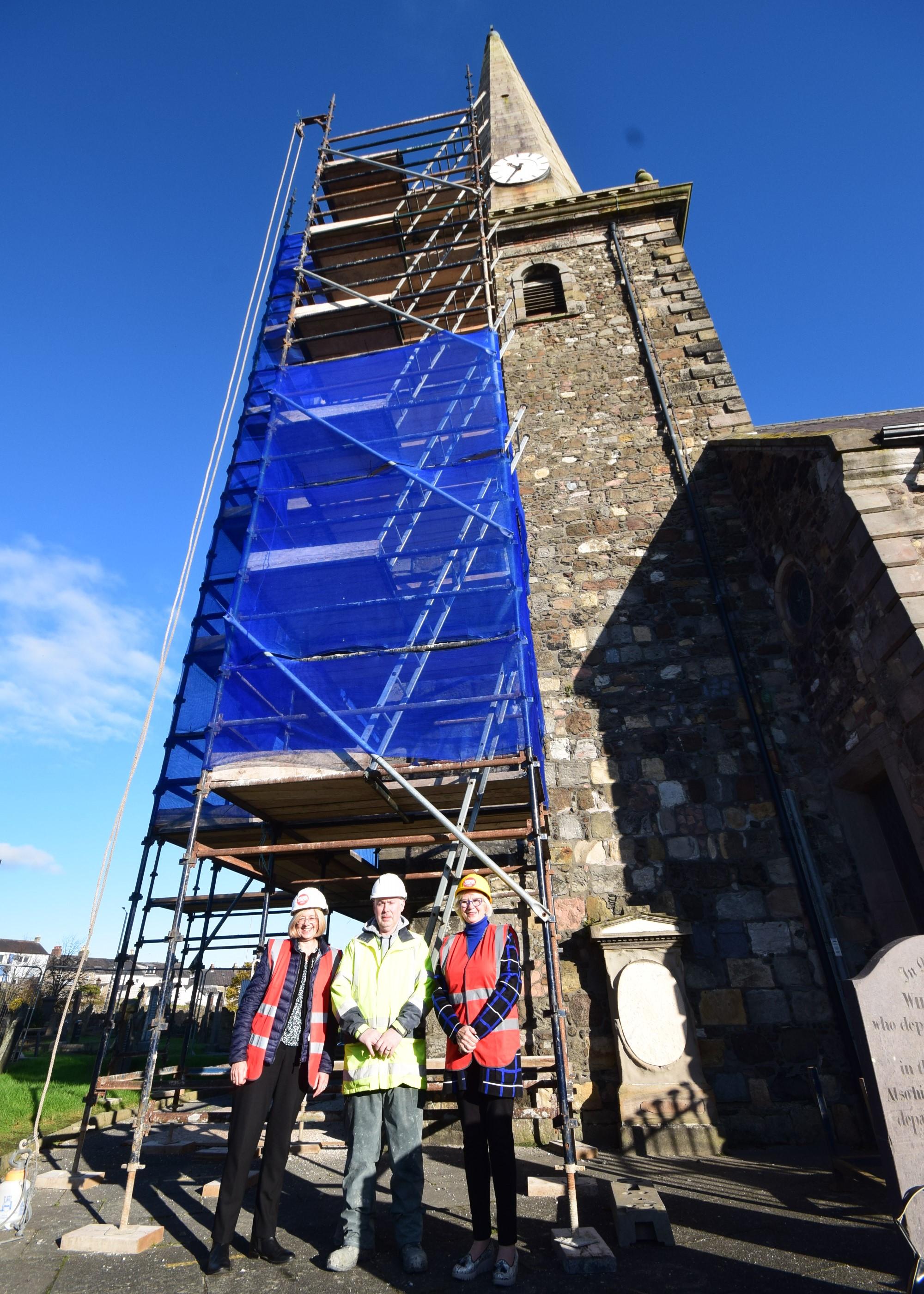 A group of people in hard hats and his-vis jackets stand outside of a church in Northern Ireland