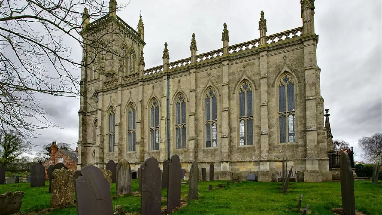 A church pictured from the side, with tall windows.