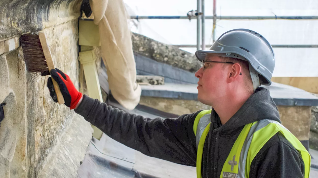 A photograph of a man brushing a wall