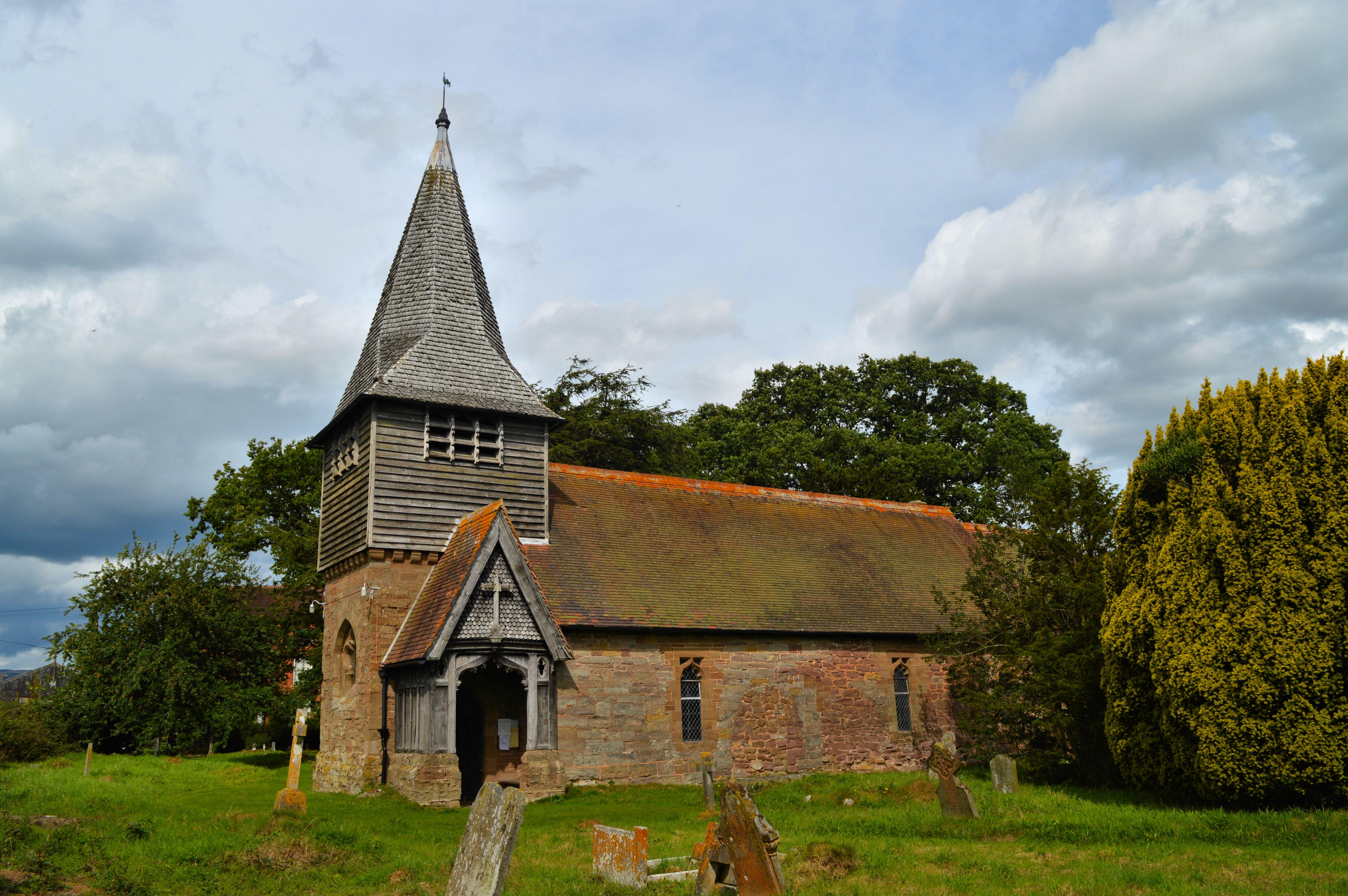 Boraston Church pictured behind a field of grass