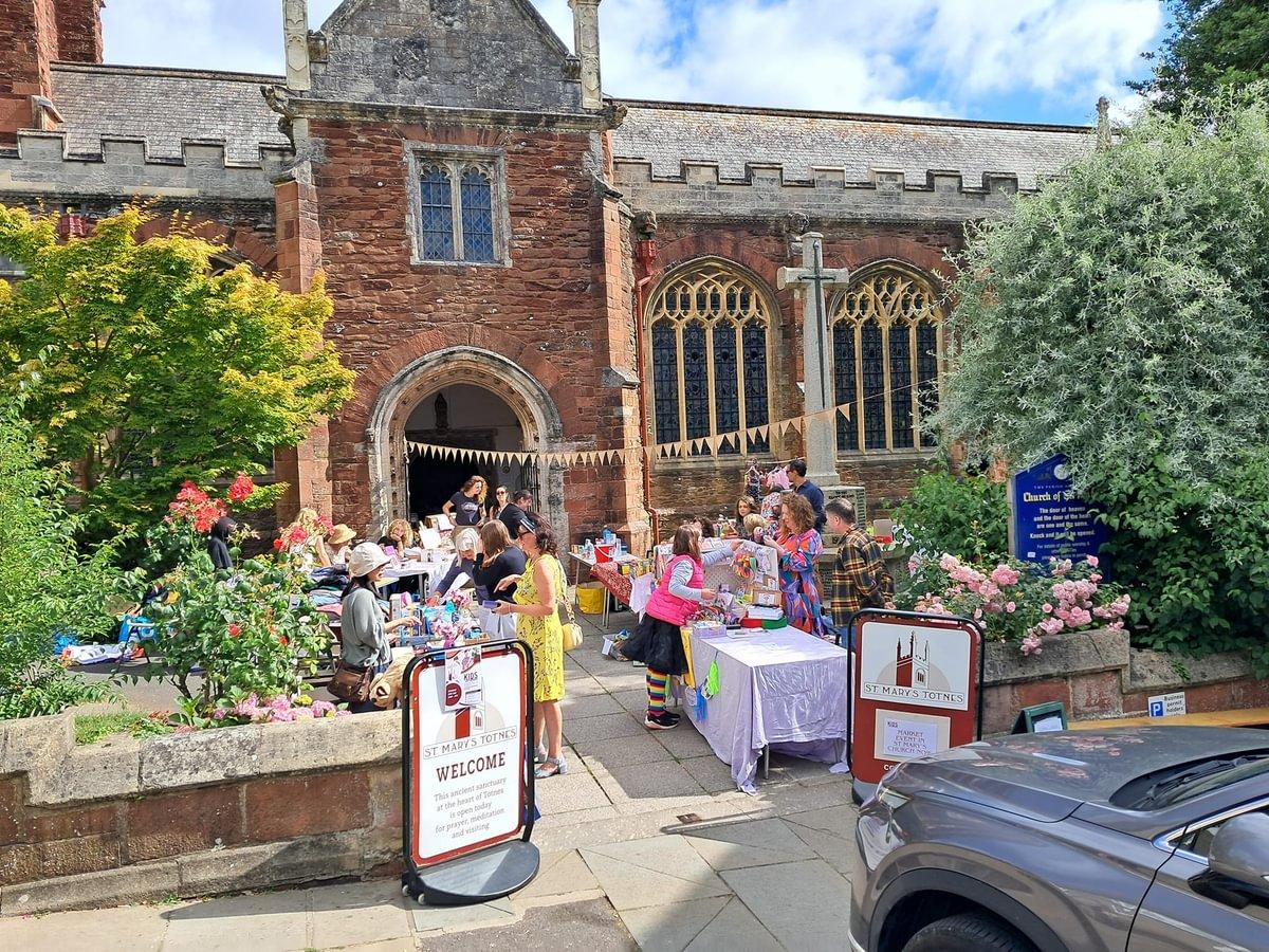 Totnes St Mary with tables and volunteers outside and a welcome sign