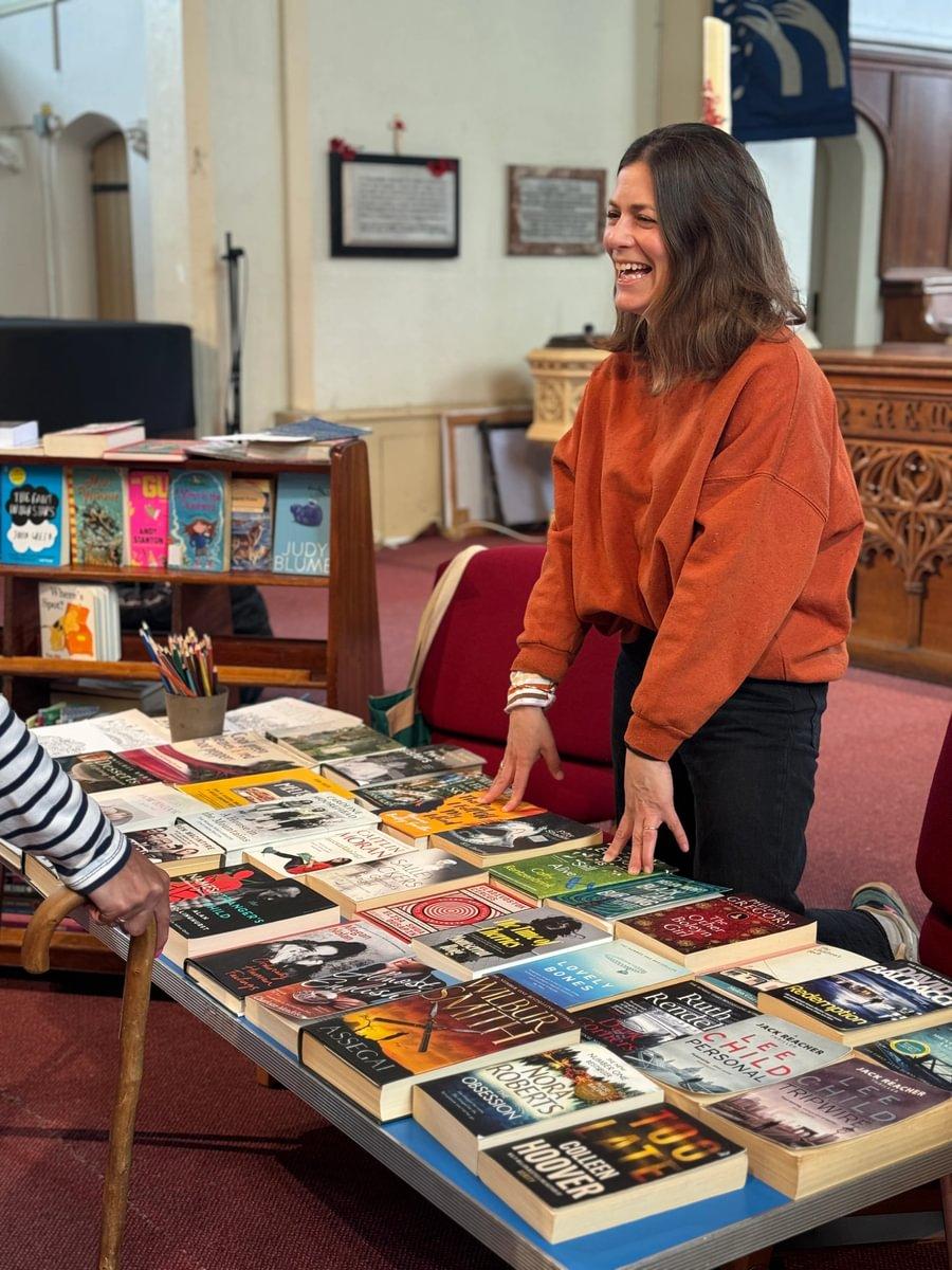 A woman stands behind a trestle table with books on it