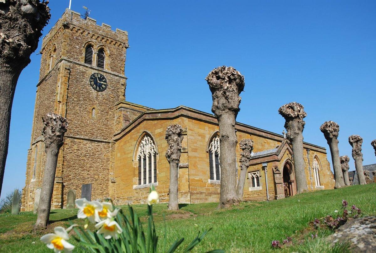 A yellow-coloured church pictured behind some flowers