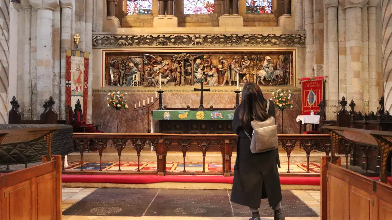 A woman stands with her back to the camera looking at beautiful art and treasures at Waltham Abbey