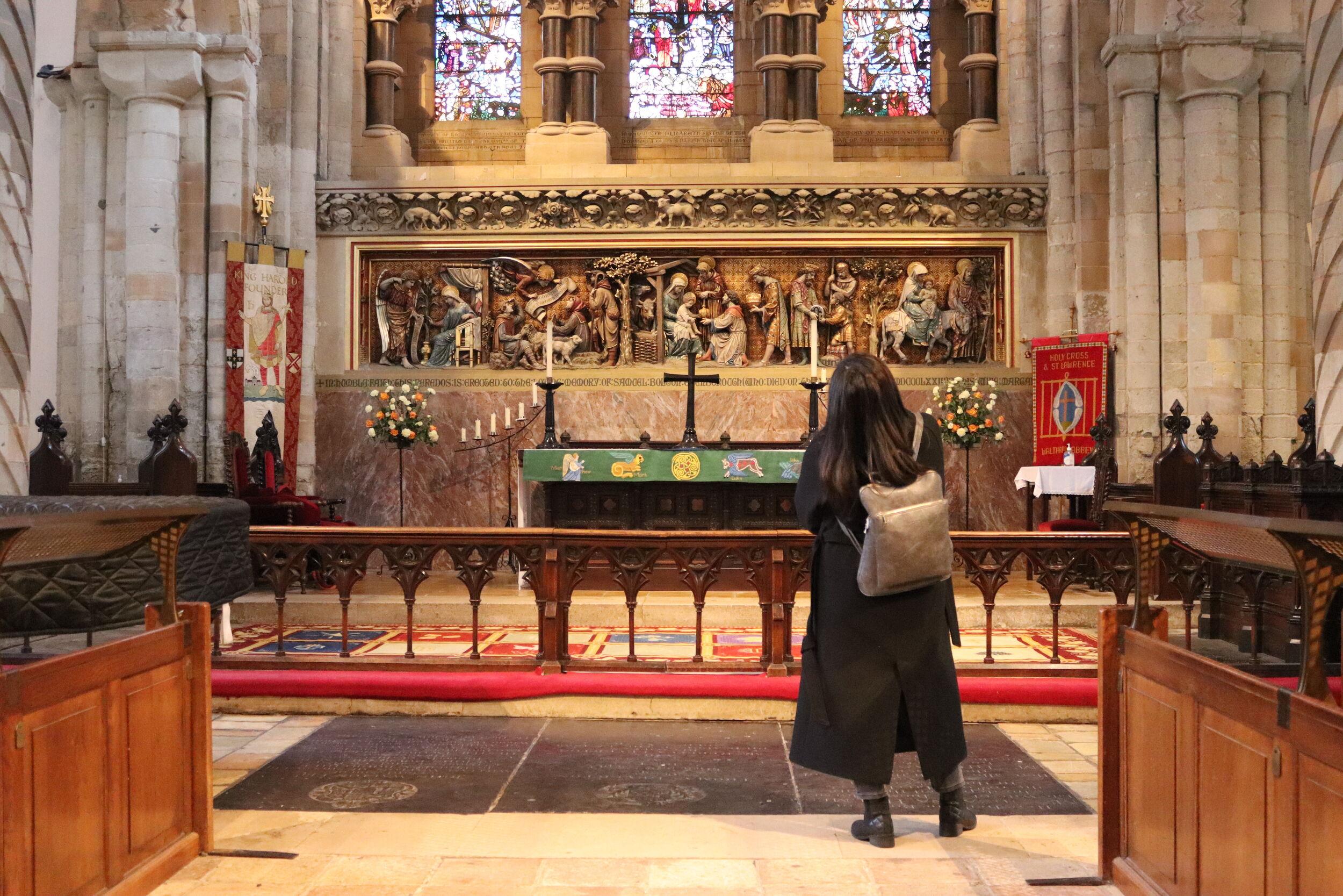 A woman stands with her back to the camera looking at beautiful art and treasures at Waltham Abbey