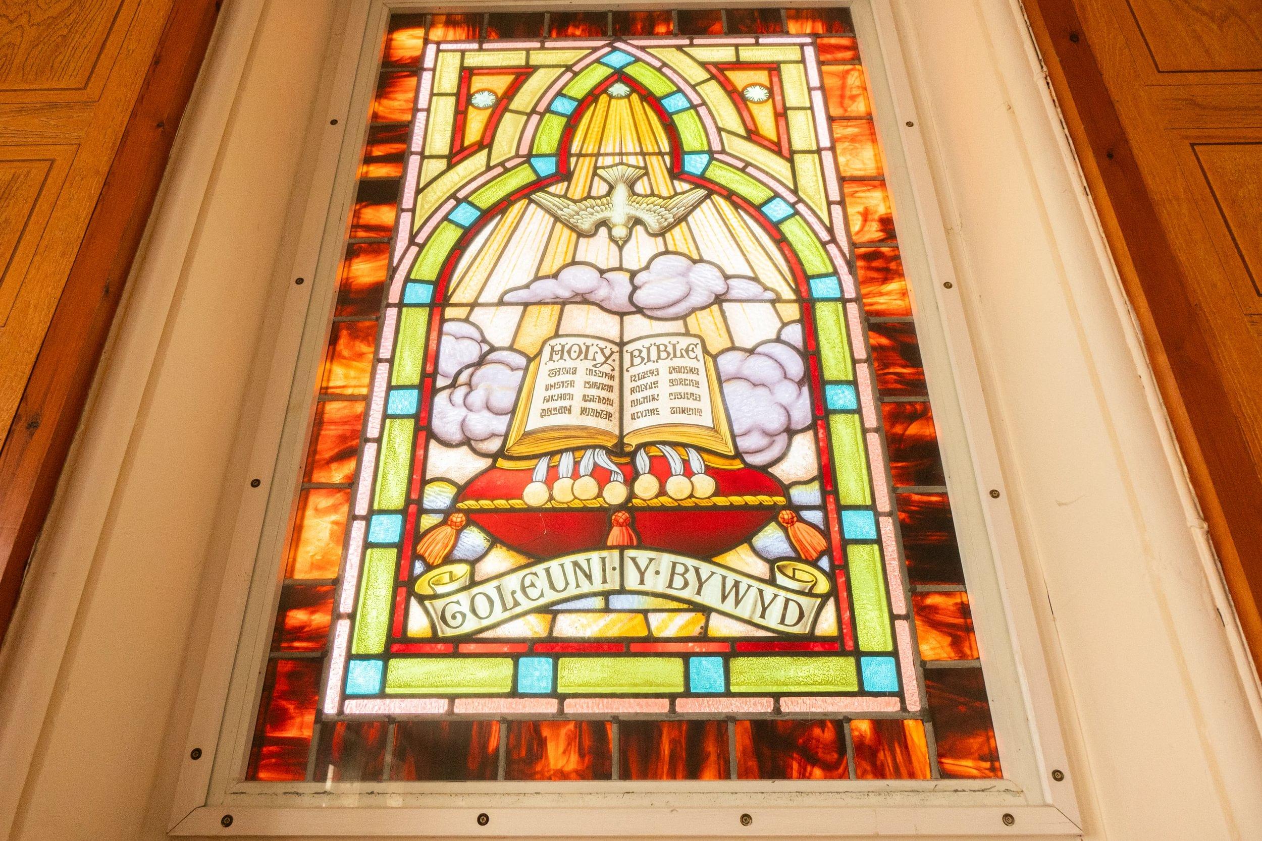A bilingual stained glass window in Bethesda Presbyterian Chapel in Mold, Flintshire. It is brightly coloured.