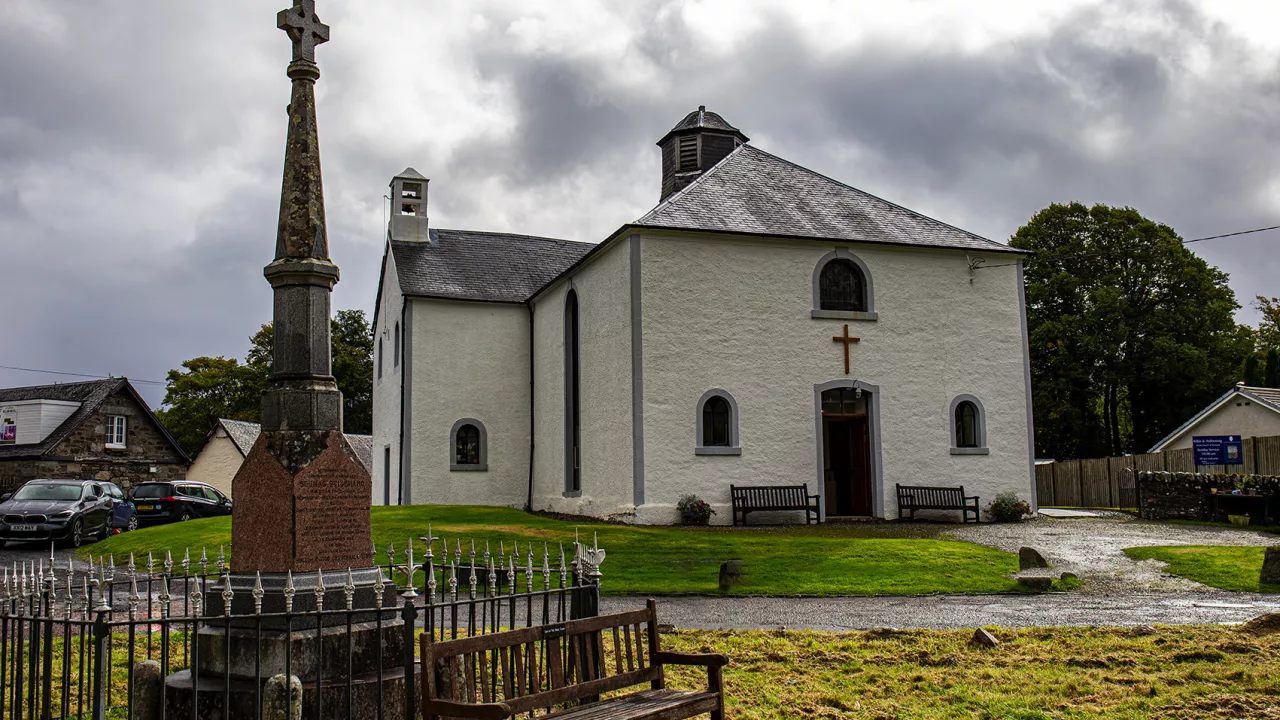 The white exterior of Killin & Ardeonaig Pairsh Church in Perthshire with a memorial to the front of the photo