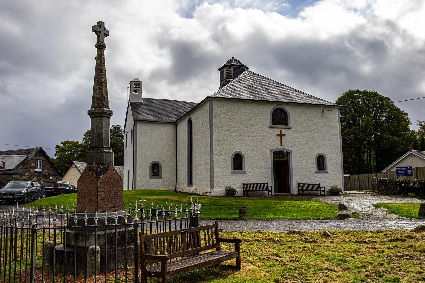 The white exterior of Killin & Ardeonaig Pairsh Church in Perthshire with a memorial to the front of the photo