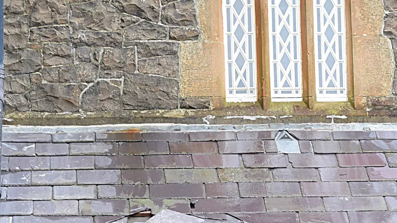 A church with many slipped tiles on its roofs following storm damage