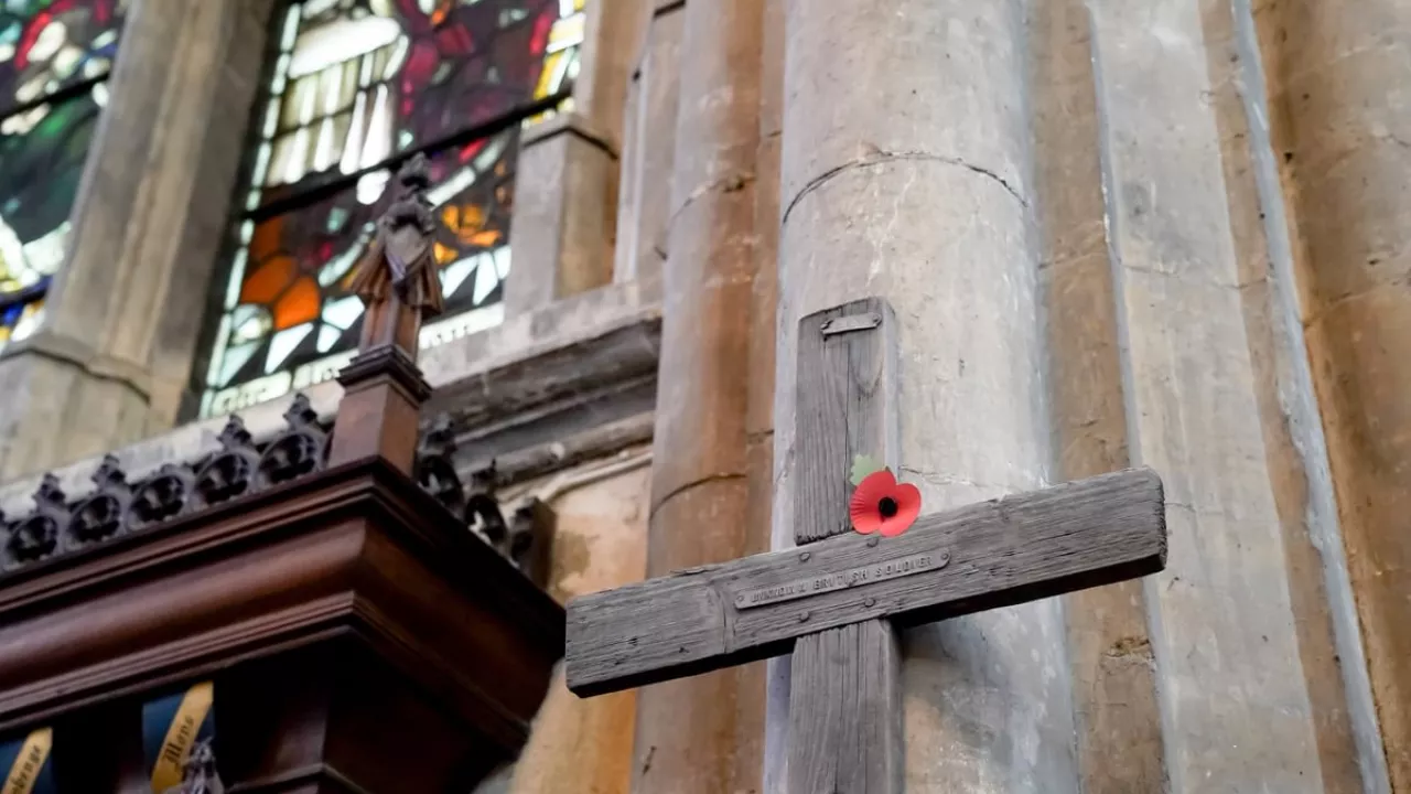 A wooden cross with a poppy attached inside a church