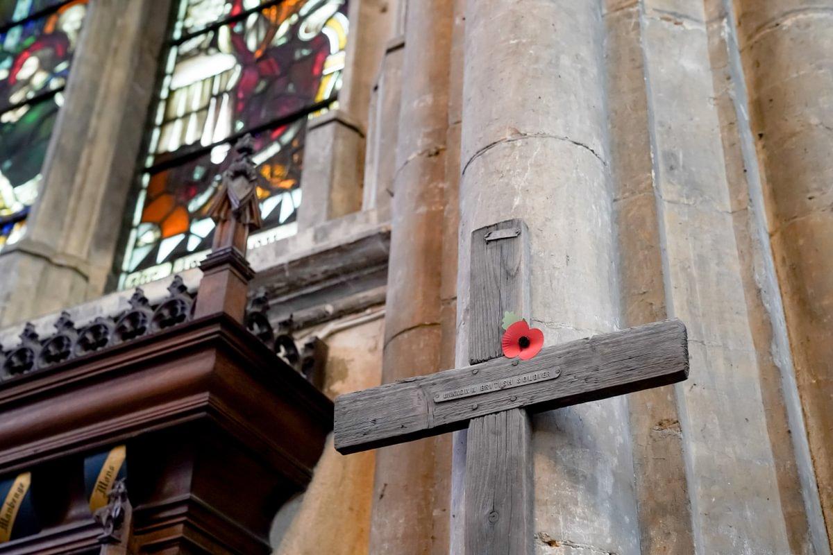 A wooden cross with a poppy attached inside a church