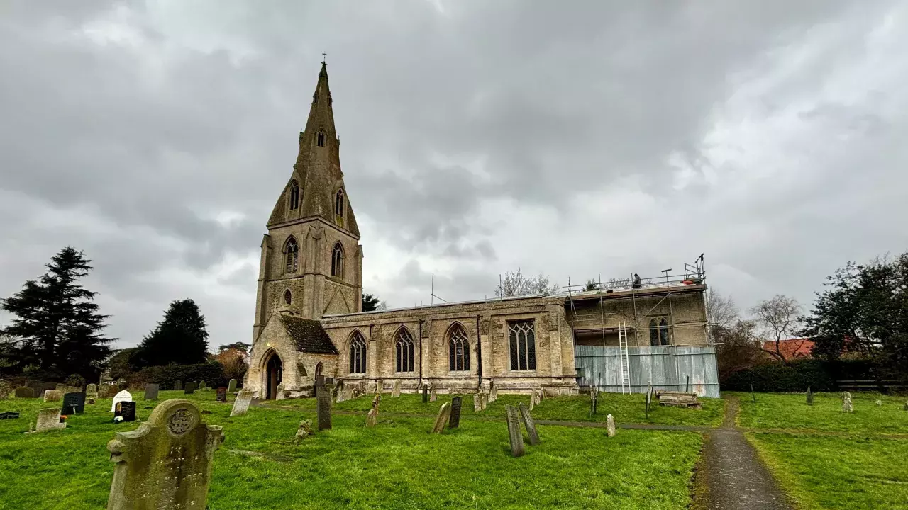 A beautiful stone church, St Peter Ad Vincula, photographed on a rainy day with men working on replacing the roof.