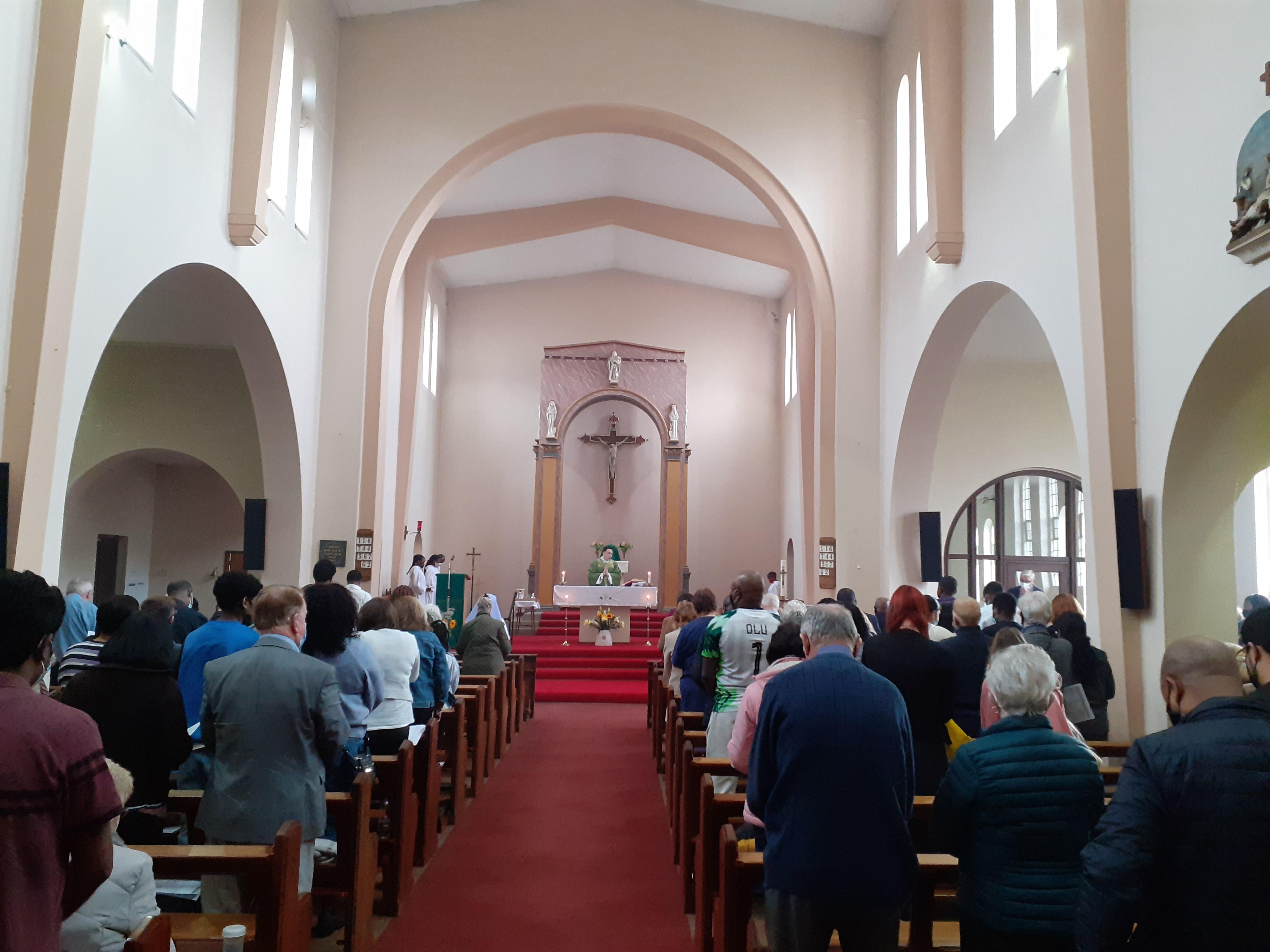 Interior of Holy Rosary Church. Rows full of people face the altar.
