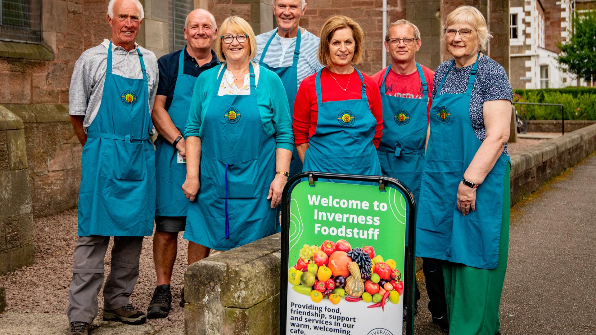 A group of volunteers wearing aprons stand outside a church