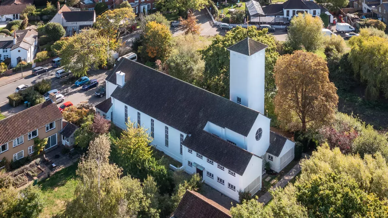 A church surrounded by bushy trees, photographed from above