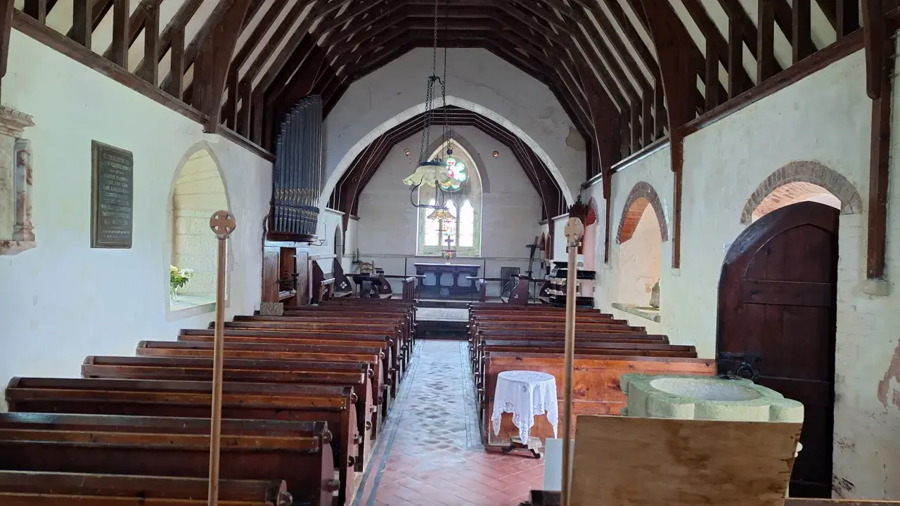 Interior of St Grada and Holy Cross; rows of pews face the altar under a timber-beamed roof