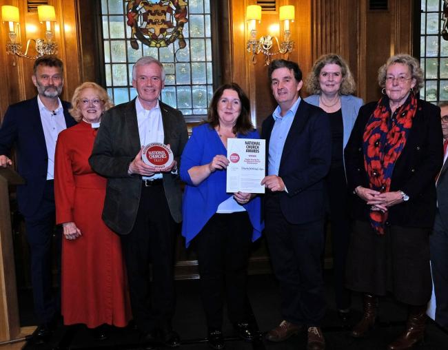 A group of people stand in a line showing their award