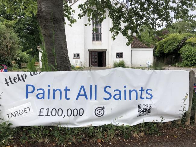 A banner outside a church reading 'Help us Paint All Saints. Target £100,000'