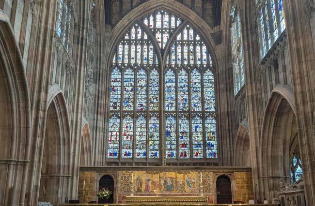 The large arched stained glass window behind an altar at Great Malvern Priory