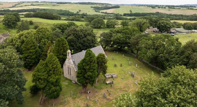 A stone church surrounded by lush green trees