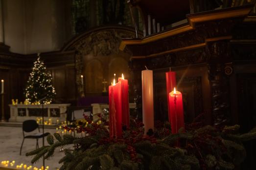 A close up of candles inside a dimly lit church at Carols by Candlelight 2022.