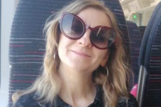 Image of a woman wearing sunglasses, smiling to the camera.