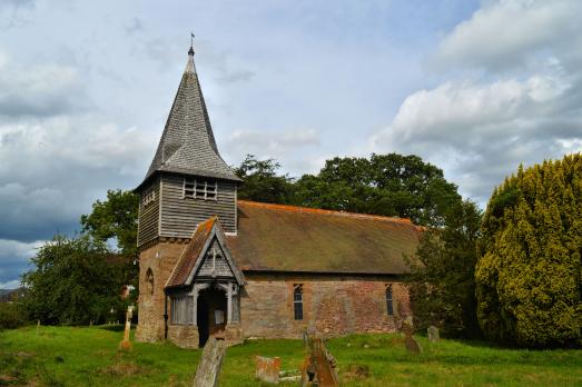 Boraston Church pictured behind a field of grass