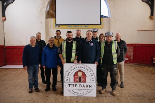A team of people - from Martins Memorial Church - stand behind a white board advertising 'The Barn'.