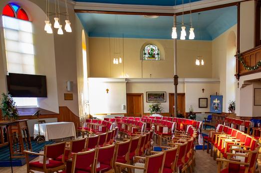The inside of Killin & Ardeonaig Parish church; a bright rom with chairs facing forwards and lovely windows