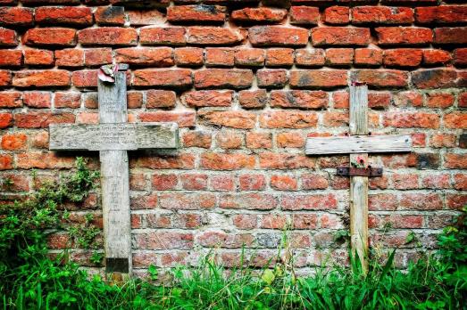 Two wooden crosses against a brick wall
